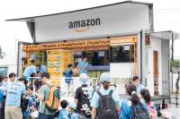 アマゾンジャパン　物流作業体験トラック稼働、自走式商品棚使った棚出し体験